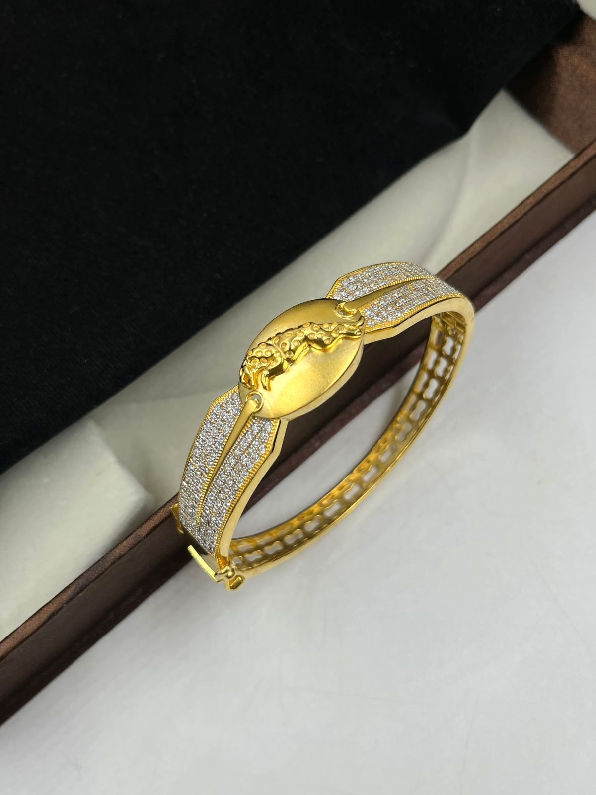 Gold bracelet with intricate design on a white surface